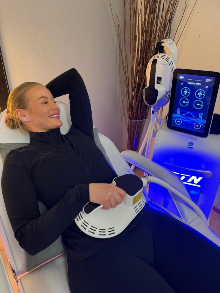 Nainen X-Tone lihasstimulaatiolaitteessa saa hoitoa vatsalihaksiin yhdellä hoitokahvalla.